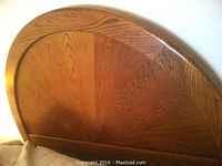Close-up photo of a solid oak queen size arched headboard showing wood grain and polished finish.