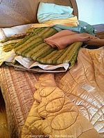 Photo of folded assorted bedding including the beige butterfly motif quilt and other blankets