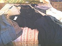 Photo of assorted ladies jackets, skirts, and sweaters in various fabrics and colors laid on a bed