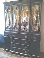 Front view of the two-piece mahogany china cabinet with curved glass panel doors, multiple drawers, and bronze-tone oval hardware pulls.