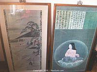 Photo showing both framed prints side by side, one showing the child on the lotus with calligraphy, the other a landscape scene.