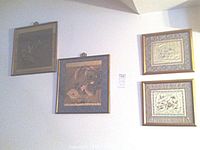 Four framed silk embroidered artworks displayed on a wall, including two smaller gilt wooden frames and two larger bamboo-style framed pieces.