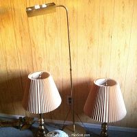 Two matching bronze tone metal table lamps with pleated white shades, and brass tone metal floor lamp visible in background