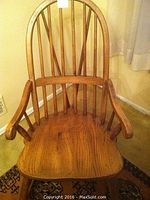 Front angle view of the solid wood rocking chair showing spindle back and armrest