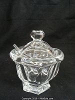 Front angle of clear Baccarat crystal condiment bowl with lid and spoon resting in the bowl opening.