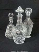 Three crystal decanters displayed together against black background.