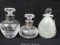 Three glass decanters shown side by side including the art glass one with a round stopper, showing overall shapes and detailed metal collars.