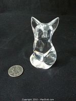 Clear glass fox figurine sitting upright beside a quarter for size comparison, on a black background.