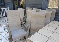 Eight beige metal-framed sling patio chairs grouped on deck