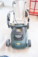 Front view of Yardworks green electric lawn mower showing handle and deck with brand and size labels.