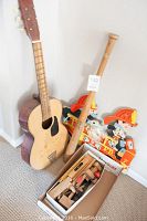 Child's acoustic guitar, box of wooden tools, and vintage fire engine coat hook wall hanging displayed together