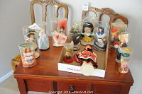 Thirteen small dolls from various travel destinations arranged on wood table, many in display tubes or cases showing cultural costumes.