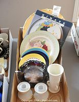 Assorted serving plates and decorative items including boxed Celina cheese platter, Royal Staffordshire floral plate, small colorful plates, a dark metal decorative piece, a white milk glass item.