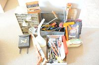Photo shows the full lot of tools including metal toolbox, small parts cabinet, hand saws, mailbox, and assorted hand tools and supplies on a carpeted floor.
