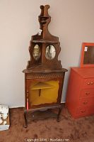 Full view of vintage wooden corner cabinet showing top decorative details, two round mirrors, glass door, and lower shelf base.