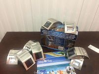 Two packs with 4 solar powered LED accent lights each, including their original boxes and unpackaged lights on a table.