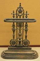 Front view of decorative cast iron fireplace tool holder with bottom tray and scrollwork