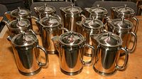 11 stainless steel coffee carafes arranged on table