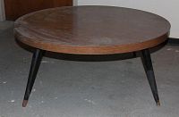 Side angled view showing circular Arborite top and four tapered black legs with worn tips.