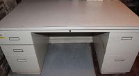 Front view of the beige metal desk showing overall structure and drawers
