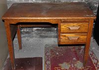 Full view of the small solid wood desk showing the top, legs, and the two drawers on the right side.