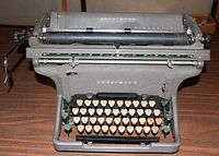 Gray Underwood manual typewriter on a wooden table showing keyboard and typebars
