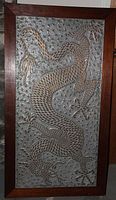Full view of rectangular decorative door panel with wood frame and brass mosaic dragon on textured green background.
