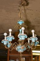Full view of the ceramic chandelier showing the blue ceramic cups for light sockets, brass arms, and hanging hook.
