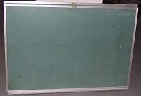 Front view of rectangular blackboard with green writing surface, metal edges, and bottom metal shelf showing scratches.