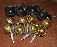 Castors with four black rubber wheels and eight brass wheels shown on a brown surface.