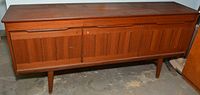Front view of wooden sideboard showing three top drawers and vertical slat cabinet doors