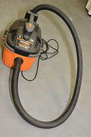 Ridgid 4 gallon WD4050 wet dry vacuum placed on floor with hose attached and power cord visible.
