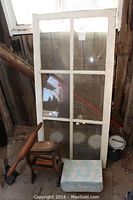 6-pane window standing upright behind shoe shine stand, rolling pin, and cushion