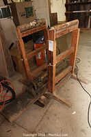 Two wooden roller supports with adjustable height and a very old lathe without motor on the floor in a workshop environment