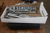 Several combination wrenches and sockets in a cardboard box showing the range of sizes and condition.