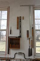 Workshop wall showing wooden and metal levels, aluminum square, chisels rack, saws, scribe