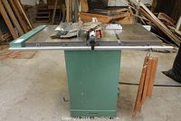 Front view of green table saw on stand showing cast iron top and side support