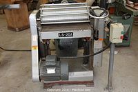 Front-angle view of the planer showing infeed table, cutter head assembly and motor beneath