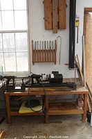 Full view of lathe mounted on wooden bench with chisels mounted on wall behind