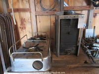 Two items: 2 burner stainless steel gas stove with metal rails and a tall marine stove heater in metal frame.