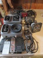 Full lot on a wooden surface showing two larger grey marine gauge units, two small black square gauges, two grey box switches with cables, and tangled cables in background.