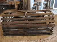 Side view of the rectangular wooden lobster trap made with slatted wood and netting inside, showing overall structure and wear.