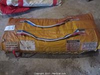 Top/front view of yellow life raft storage bag showing warning label and tri-color handles.