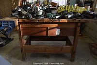 Wooden work table with various power tools and air hose on top, vise visible on left