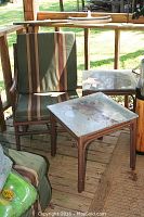 Patio chair with striped cushions and one matching glass top side table with decorative lion image.