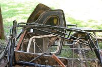 Photo showing various rusted Jeep parts including two door frames, metal tubing, and other components piled outdoors on a trailer.