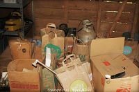 Photo showing cardboard boxes and paper bags containing various plumbing fittings and hardware, with a large propane tank visible