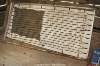 Full view of the antique metal screen door laid flat, showing the spring mesh stretched across the frame.