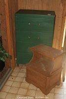 Green painted chest of drawers with four drawers and side table with natural wood finish.
