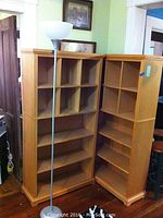 Photo showing both wooden shelves positioned next to each other with lamp and part of furniture in the background.